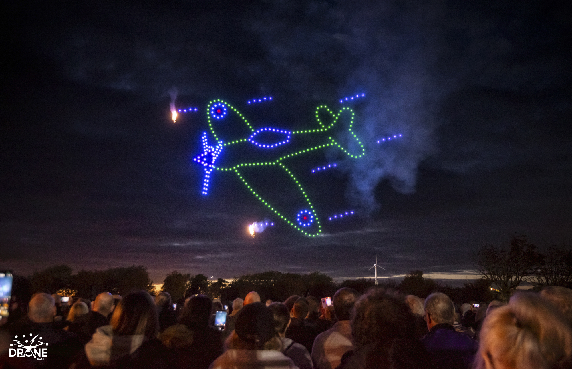 A colourful aircraft formed by drones and effects above a live audience