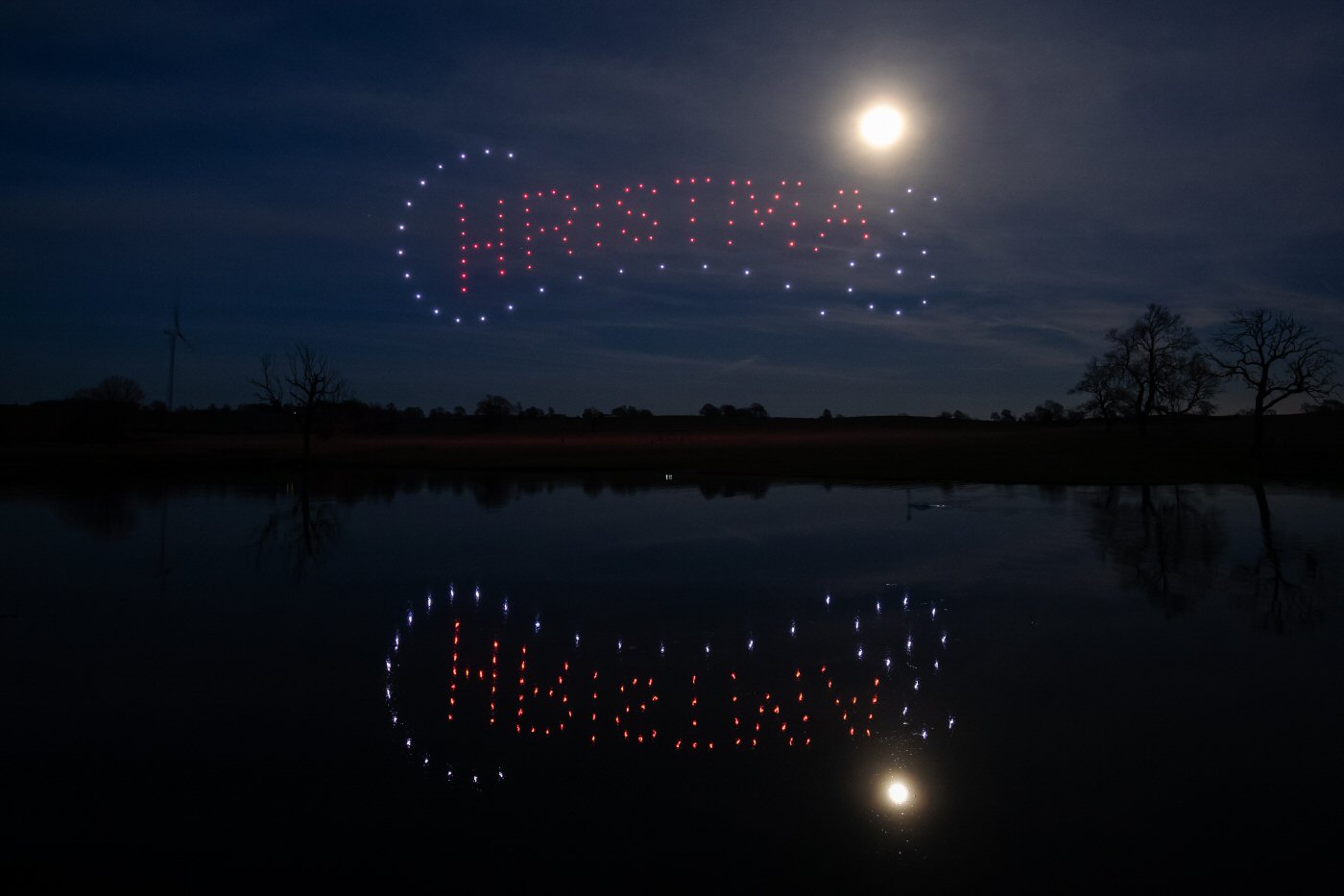 Happy Xmas message created by a DroneSwarm Christmas drone light show above a lake
