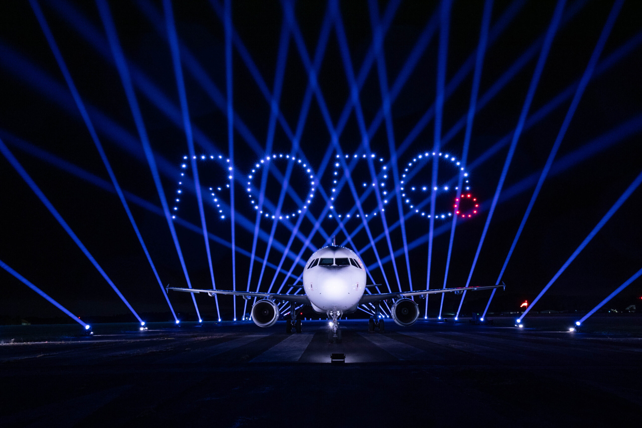 ROBE logo formed by illuminated drones above an aircraft and blue event lighting
