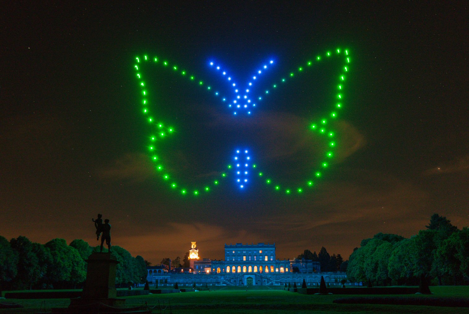 Colourful butterfly drone formation above a country house