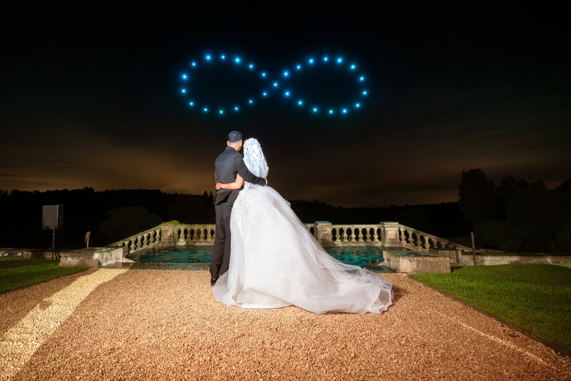 Newlywed couple watching a drone light show at night