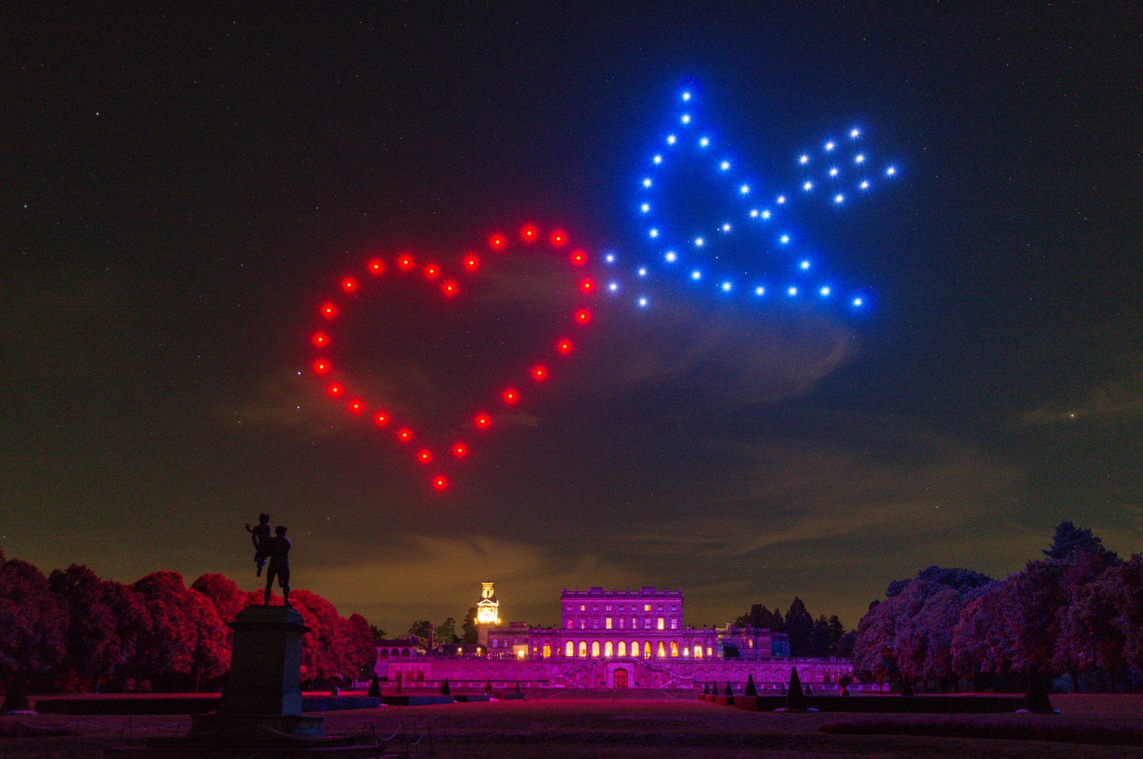 Heart and dove drone formation above an illuminated wedding venue