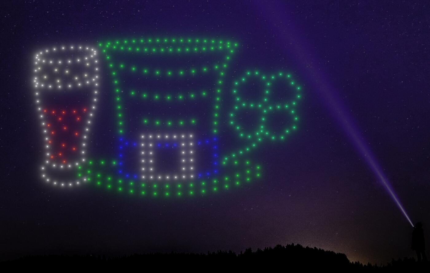 A night sky features a mesmerizing drone light show displaying a beer glass, leprechaun hat, and shamrock in green, blue, and red lights.